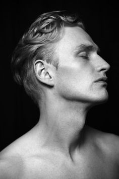 a black and white photo of a man with his head turned to the side looking up