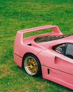 a pink sports car parked in the grass