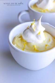 two white bowls filled with pudding topped with whipped cream and lemon zest on top