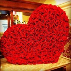 a large heart made out of roses on top of a wooden table in front of a mirror