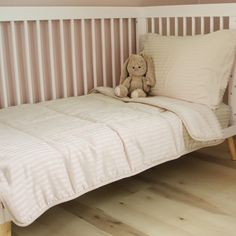 a teddy bear sitting on top of a bed next to a pillow and blanket in a child's room