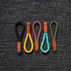 four different colored lanyards are lined up on a gray surface, one is yellow and the other is green