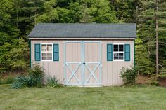 a small shed sitting in the middle of a lush green field with trees behind it