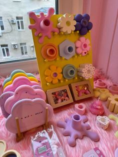 there are many different toys on the pink carpet in front of a window and a yellow frame