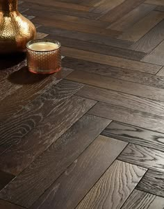 a wooden floor with a vase and candle on it, next to the wood floor