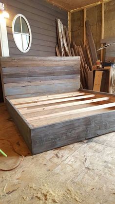 a bed frame made out of wood sitting on top of a floor next to a window