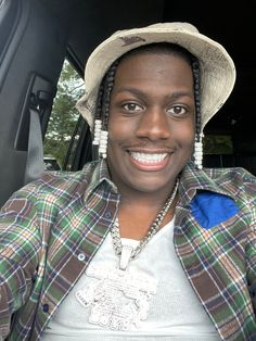 a man wearing a hat sitting in the back seat of a car with his hands on his hips