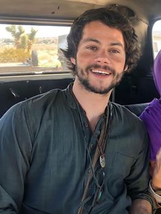 a man and woman sitting in the back of a car smiling at the camera while wearing headscarves