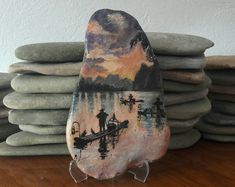 a rock with a painting of a man on a boat in the water next to stacks of rocks