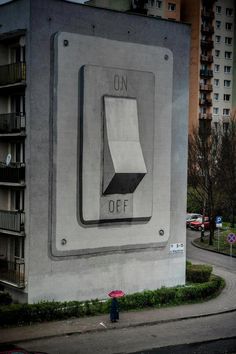 a person with an umbrella standing in front of a large sign on the side of a building