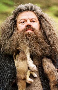 a man with long hair holding two kittens on his shoulders and looking up at the sky