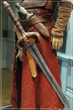 an image of a man dressed in medieval clothing with two swords and gloves on his hands