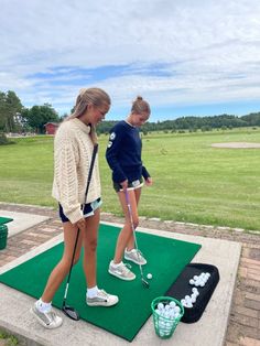 two girls playing mini golf on a green course