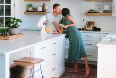 a man and woman standing in a kitchen next to each other with mixers on the counter