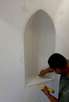 a man holding a banana in front of a white wall with a shelf on it