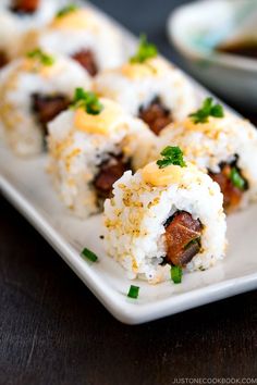 sushi rolls on a white plate with sauce and garnish