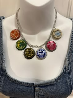 a white mannequin wearing a necklace with different colored beer caps attached to it