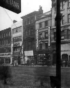 an old black and white photo of people walking down the street in front of buildings