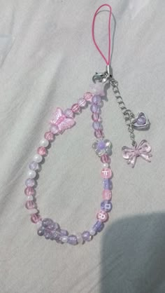 a pink and purple beaded bracelet with charms on it's end is laying on a white sheet