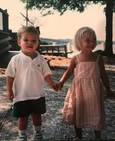 two young children holding hands while standing next to each other