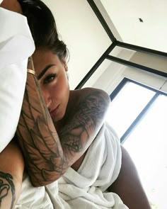 a woman with tattoos on her arm laying in bed