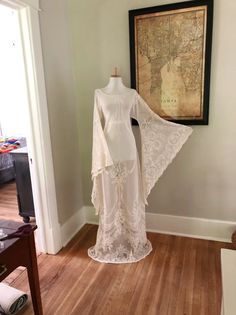 a white dress is on display in a room with wood floors and a framed map