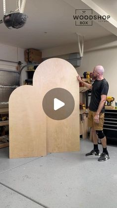 a man standing next to a large wooden object in a room with tools on it