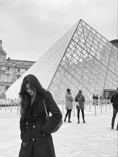 a woman standing in front of a large pyramid with her hand on her hip while looking at her cell phone