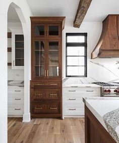 an empty kitchen with wooden cabinets and marble counter tops, along with hardwood flooring