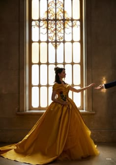 a man and woman dressed in yellow are standing by a window with their arms outstretched