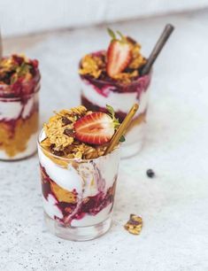 two glasses filled with yogurt, granola and strawberries