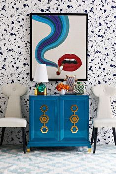 a blue cabinet with two white chairs and a painting on the wall above it that says instagram