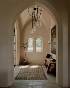 an archway leading to a living room with two windows and a rug on the floor