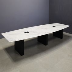 a white marble table with black legs in an empty room next to a gray wall