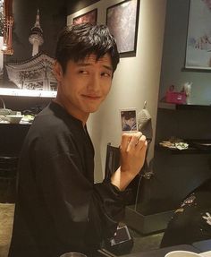 a man holding up a cell phone in front of his face at a restaurant table