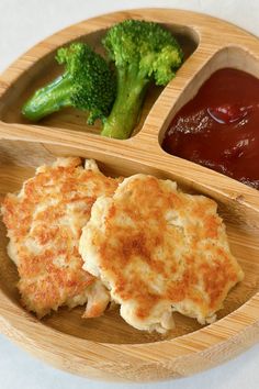 a wooden plate topped with three different types of food next to sauce and broccoli