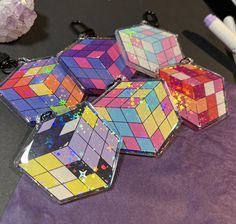 four different colored rubik cubes sitting on top of a purple cloth next to some scissors