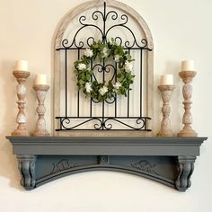 a mantle with candles and a wreath on it