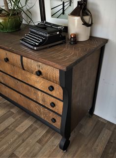 an old fashioned dresser with a black typewriter on it's top and drawers