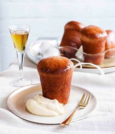 a muffin on a plate with whipped cream and a glass of wine next to it