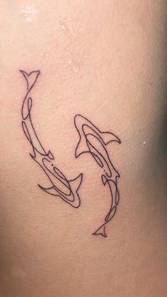 a woman with a tattoo on her back showing two dolphins swimming in the ocean together