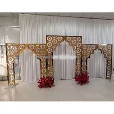 an elaborately decorated room with white drapes and red flowers in vases on the floor