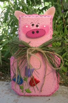 a pink pig planter sitting on top of a cement slab with grass growing out of it