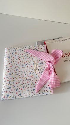 a book with a pink ribbon tied to it's cover on top of a table