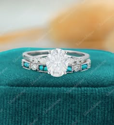 an engagement ring with blue stones and diamonds in it on top of a green velvet box