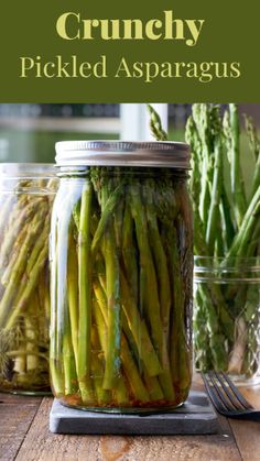 jars filled with pickled asparagus on top of a wooden table