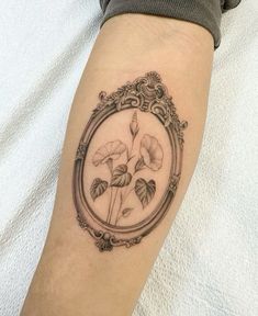 a woman's arm with a tattoo on it that has flowers in the frame