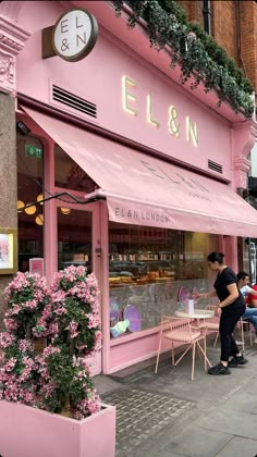 a pink store front with people sitting at tables outside