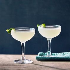 two martini glasses with lime garnish sit on a table