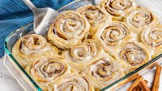 cinnamon rolls in a glass baking dish with cinnamon sticks